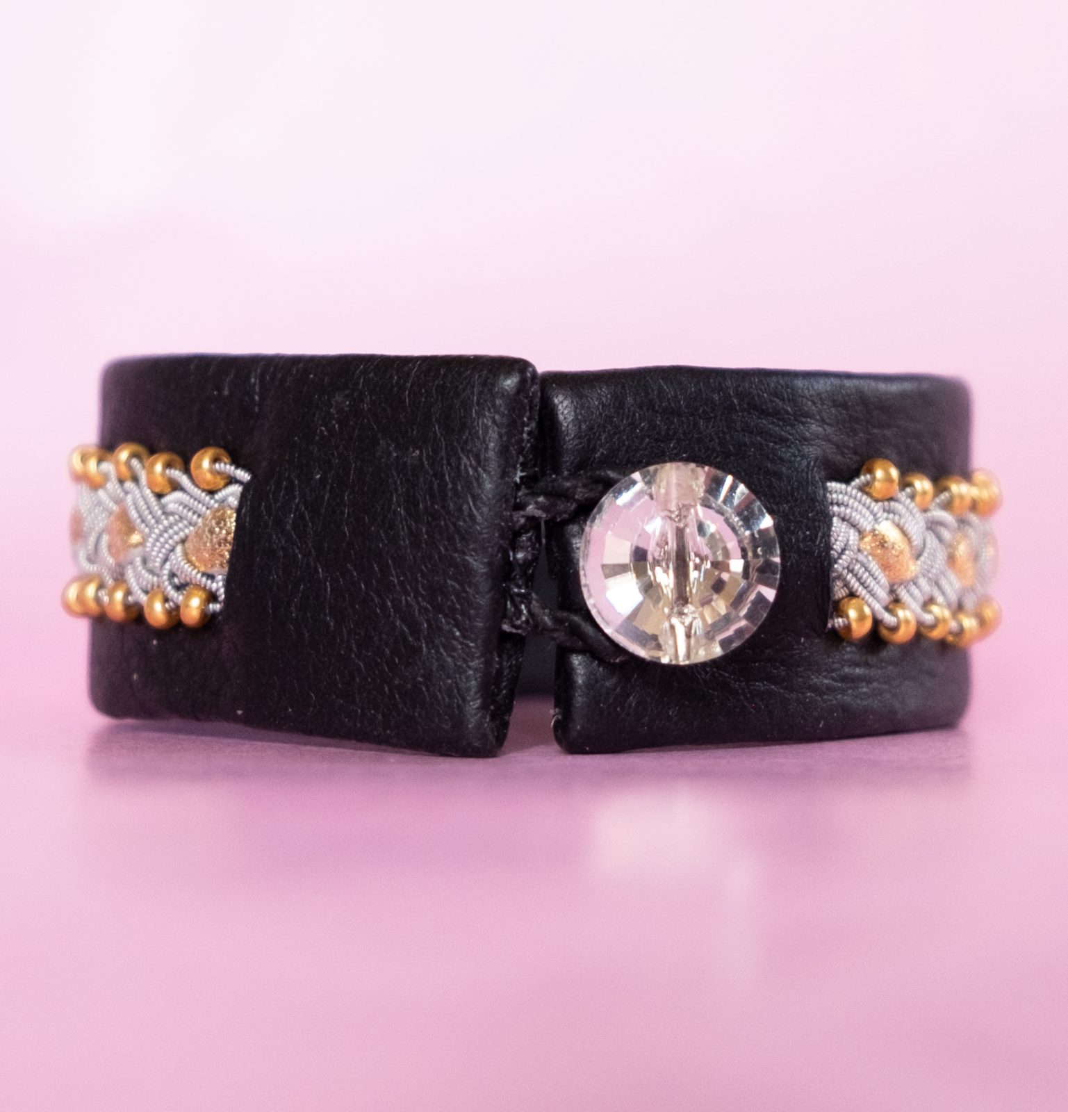 LYDIA - Svart tenntrådsarmband med guldfärgade pärlor och skinnband. Glasknapp i Swarovskistil